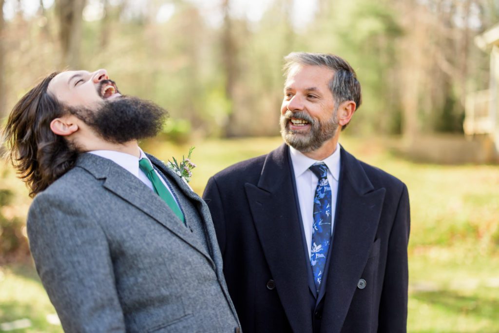 groom laughing with father before windy spring charlottesville wedding