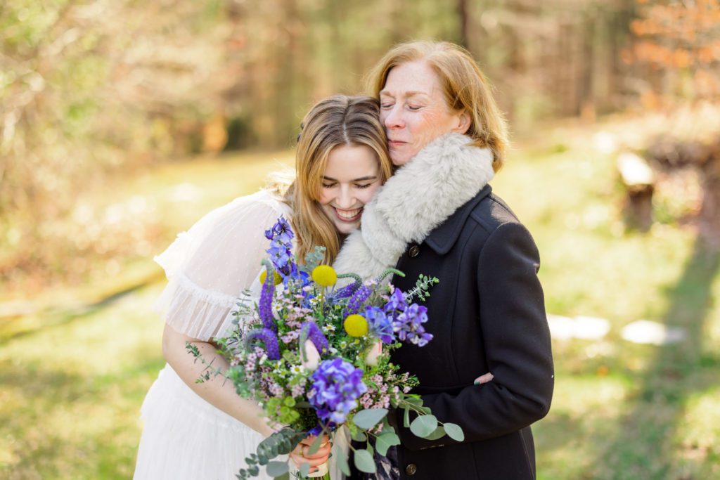bride hugging family while holding purple flowers 