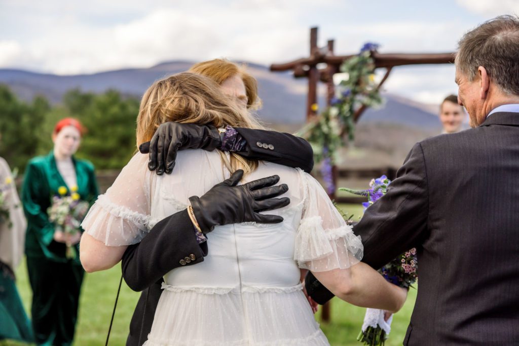 bride hugging mother and father before getting married in outdoor boho wedding ceremony