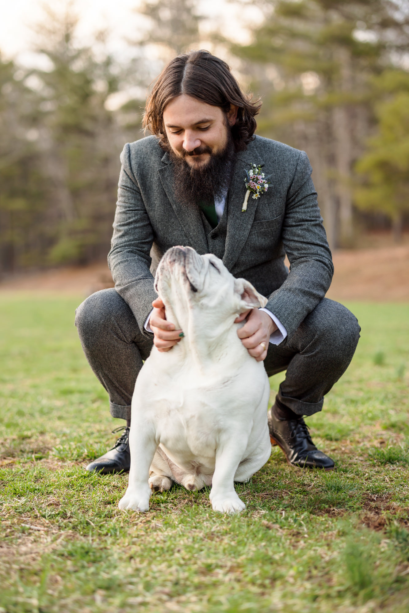 groom on ground holding and petting dog after ceremony