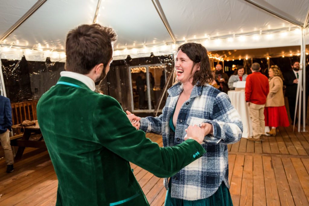 wedding guest wearing plaid shirt and green velvet jacket dancing on dance floor 