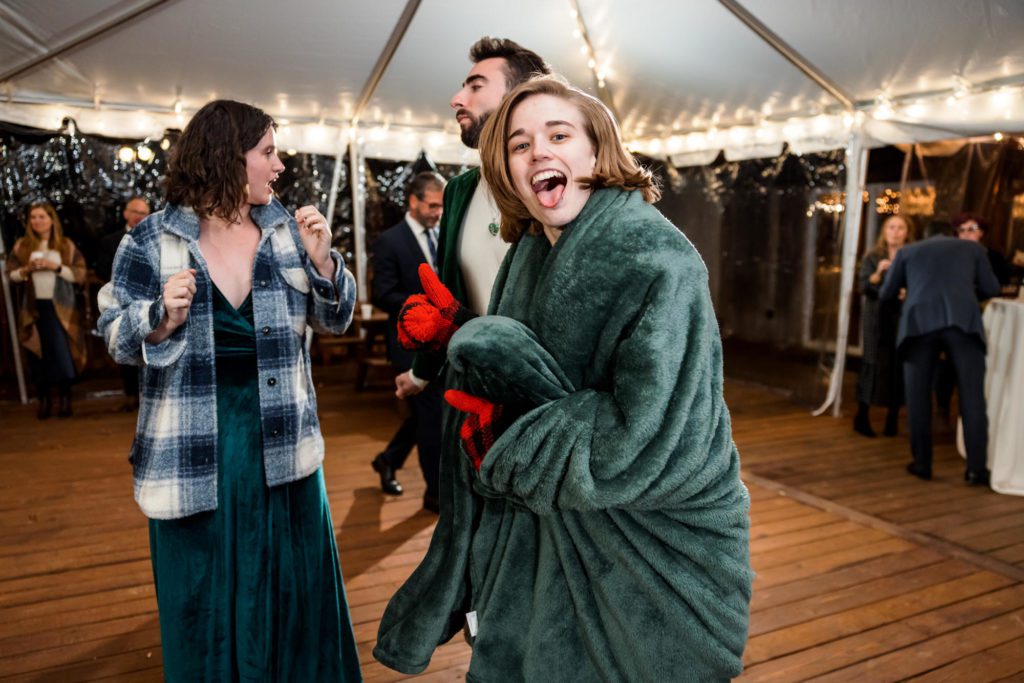 wedding party dancing and having fun during outdoor wedding reception wearing blanket and gloves