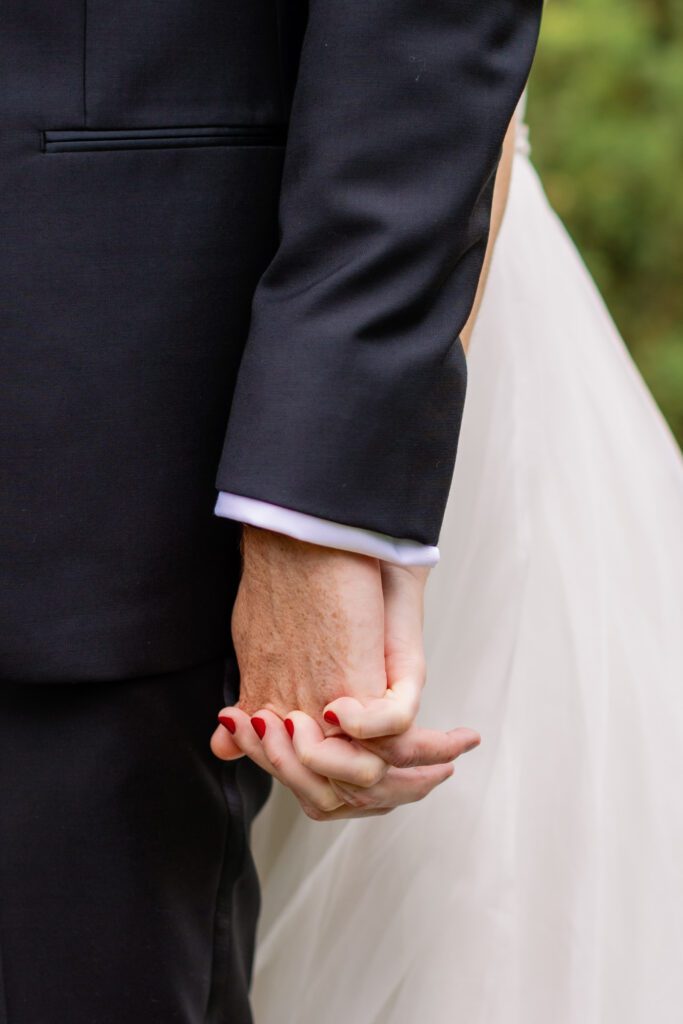 close up of bride and groom holding hands before first look on wedding day