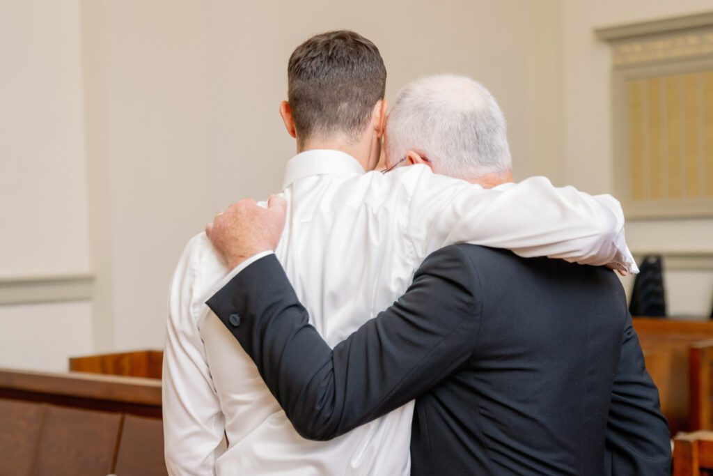groom's father hugging groom 