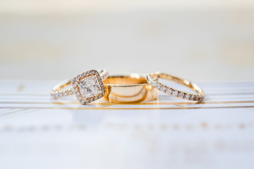 gold wedding rings detail shot with large solitaire diamond engagement ring