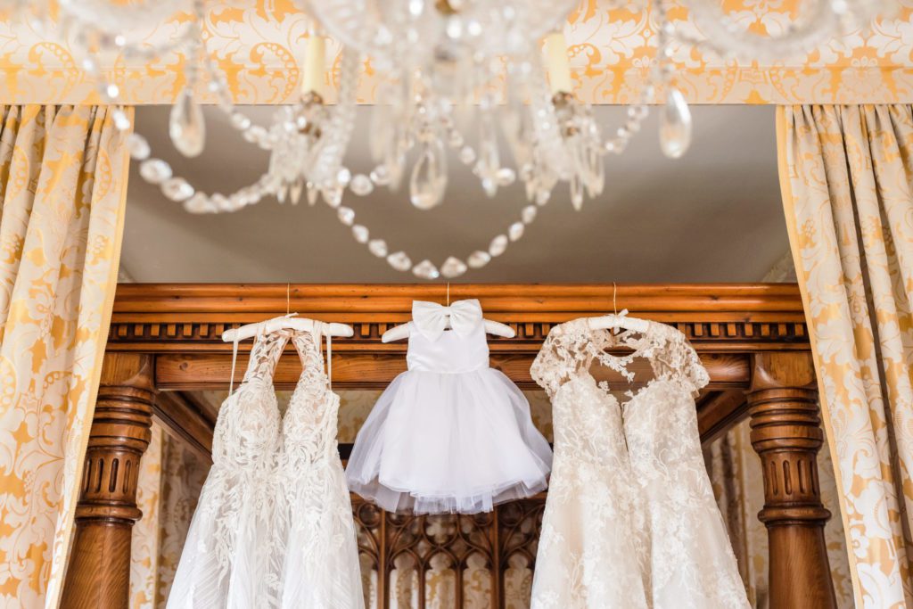 three dresses hanging from banister with flower girl dress in middle 