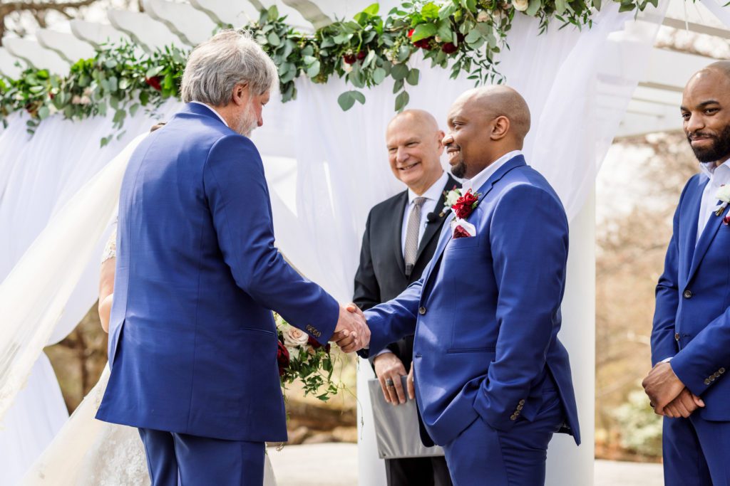 bride's father shaking groom's hand after walking bride down the aisle