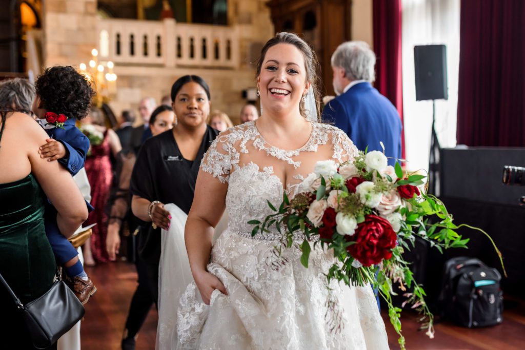 bride carrying bouquet while holding gown and walking after wedding ceremony