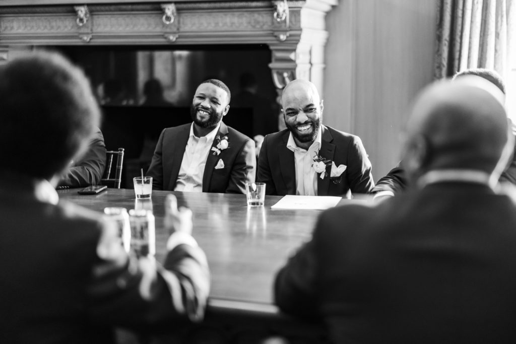 groom sitting and laughing with friends and other groomsmen during reception