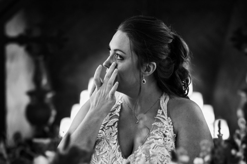 bride getting emotional and wiping away tears during bridesmaids' toast at wedding reception