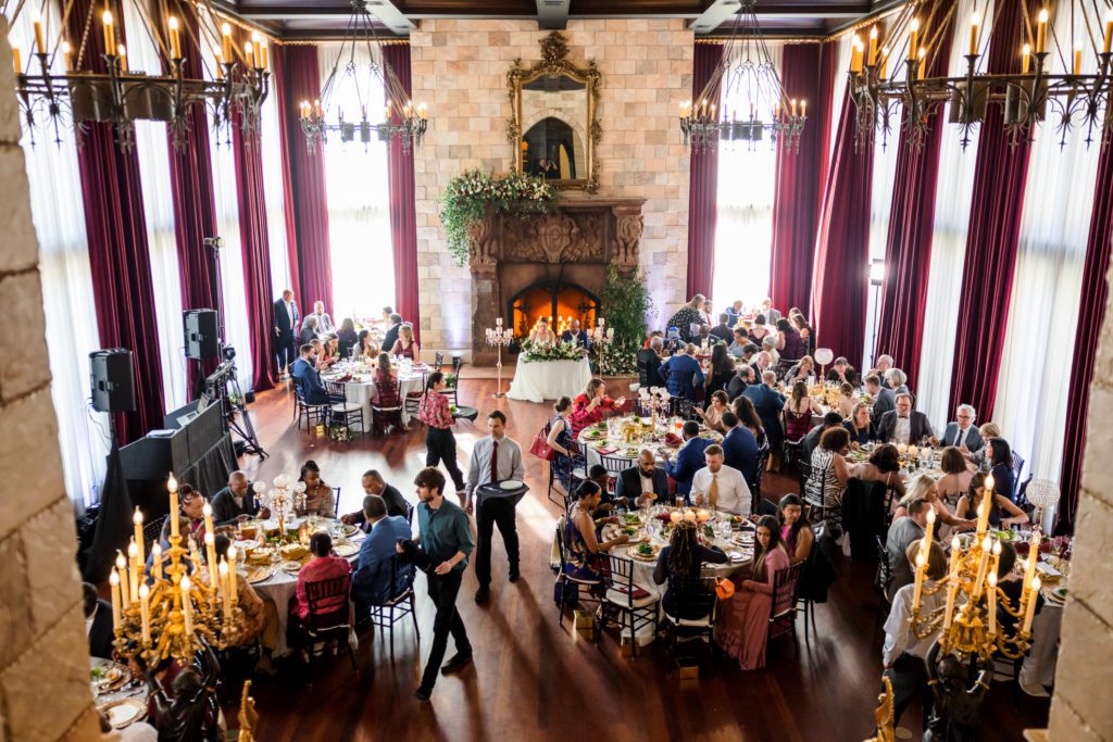 overview of wedding reception hall with guests sitting at tables and enjoying events