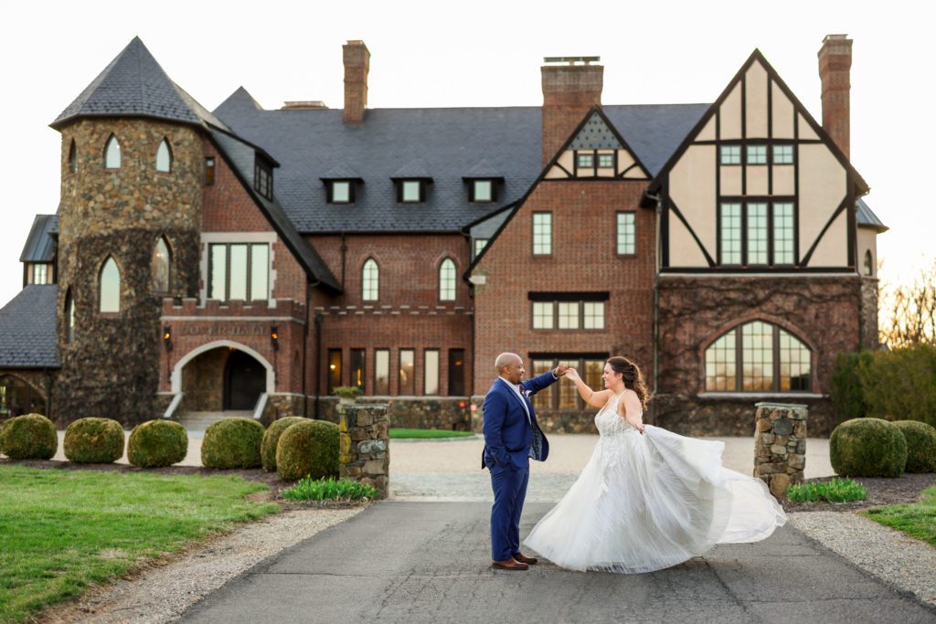 groom spinning bride during portraits in front of Dover Hall wedding venue