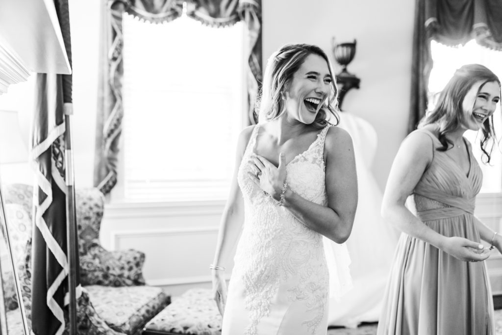 black and white portrait of bride laughing while getting ready before wedding