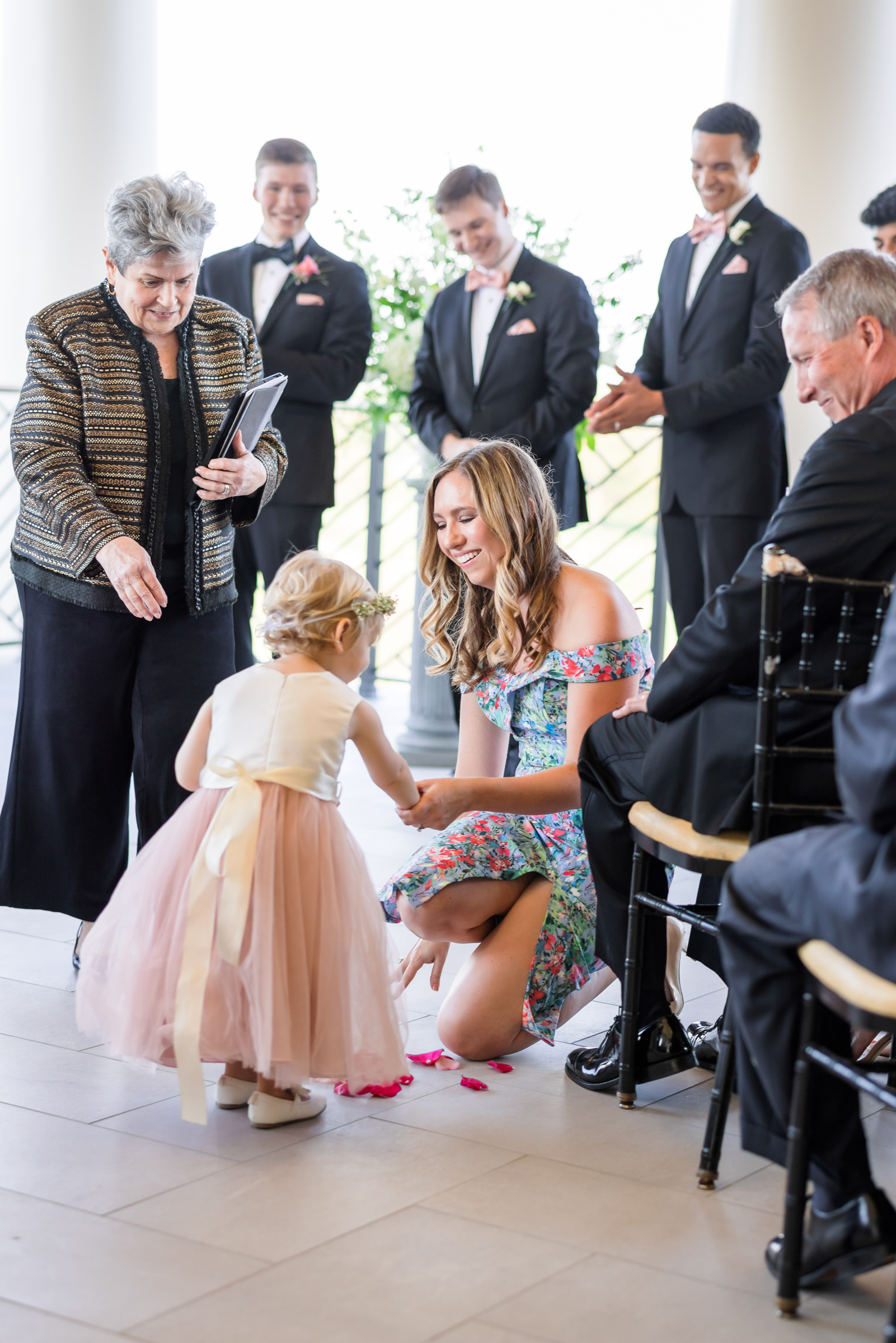 woman helping flower girl throw petals during ceremony