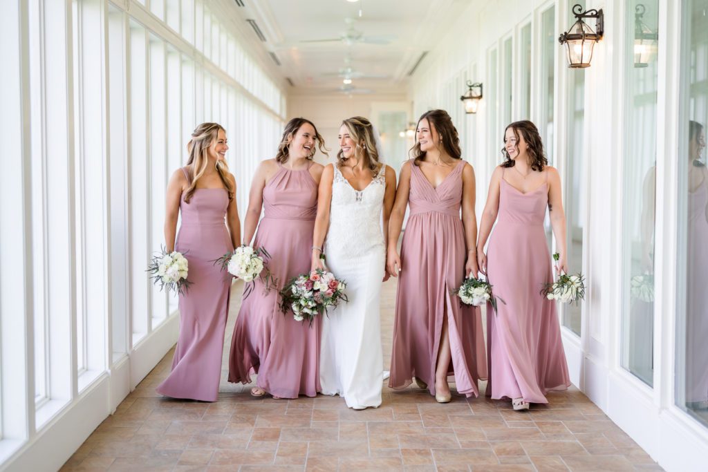 bride walking with bridesmaids wearing pink dresses and holding bouquets