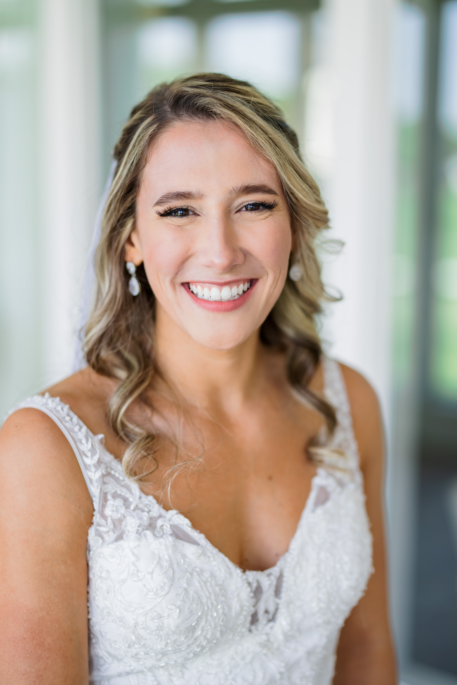 bride smiling with hair half up and half down wearing lace gown