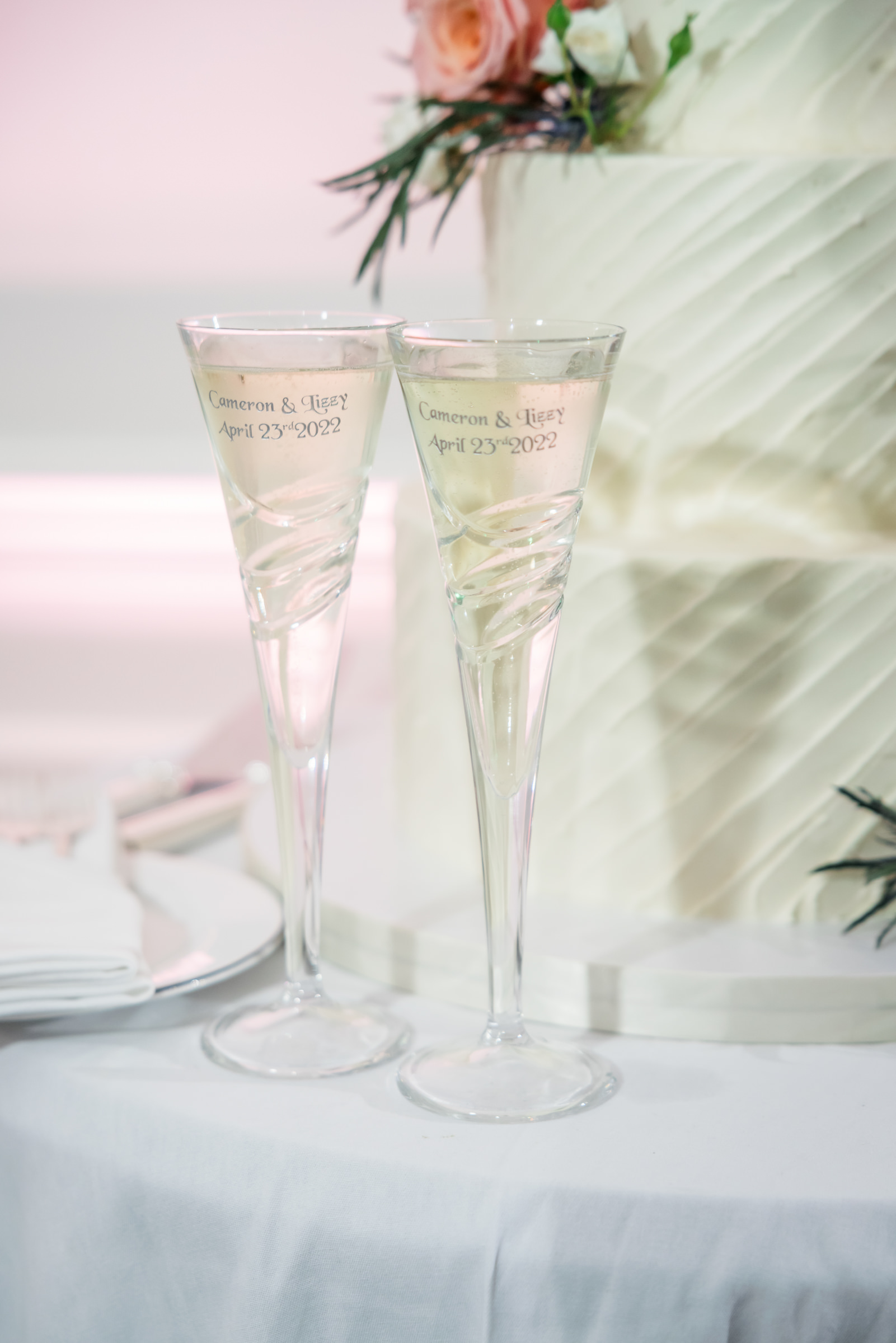 two champagne flutes sitting by wedding cake