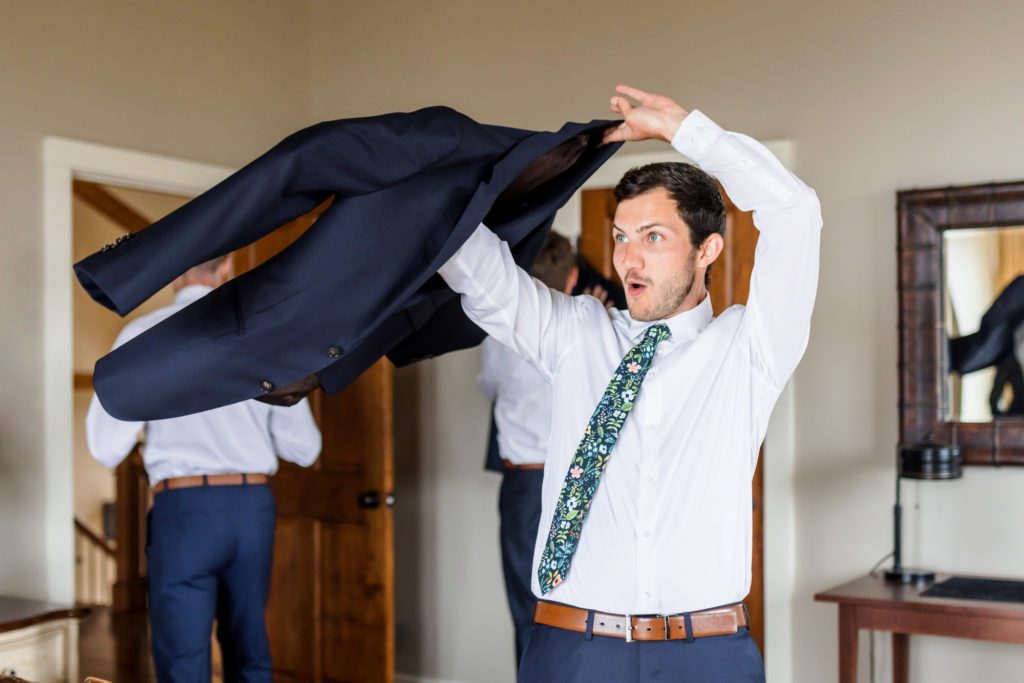 man putting on jacket while getting ready for wedding