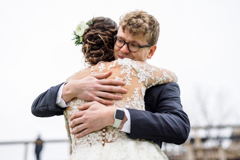 bride hugging brother during first look before wedding ceremony 