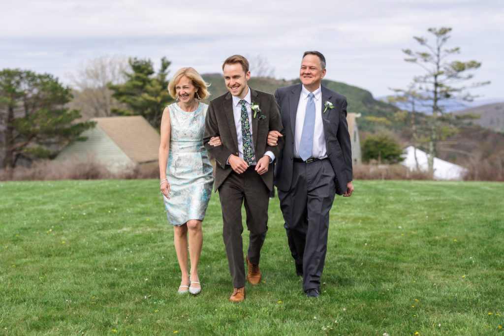 groom walking into ceremony with parents on each arm