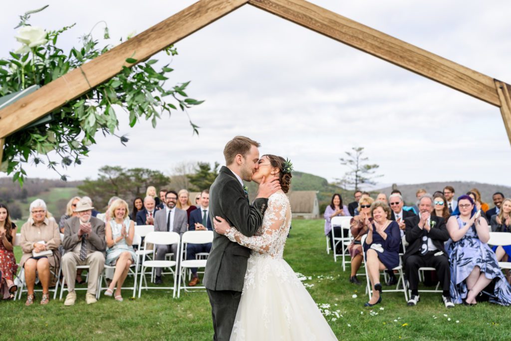 wedding couple kissing for the first time as husband and wife after spring outdoor wedding ceremony