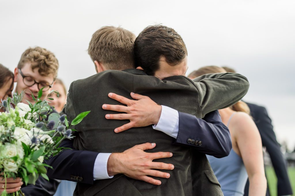groom hugging wedding guests after spring outdoor wedding ceremony at 12 Ridges Vineyard wedding 