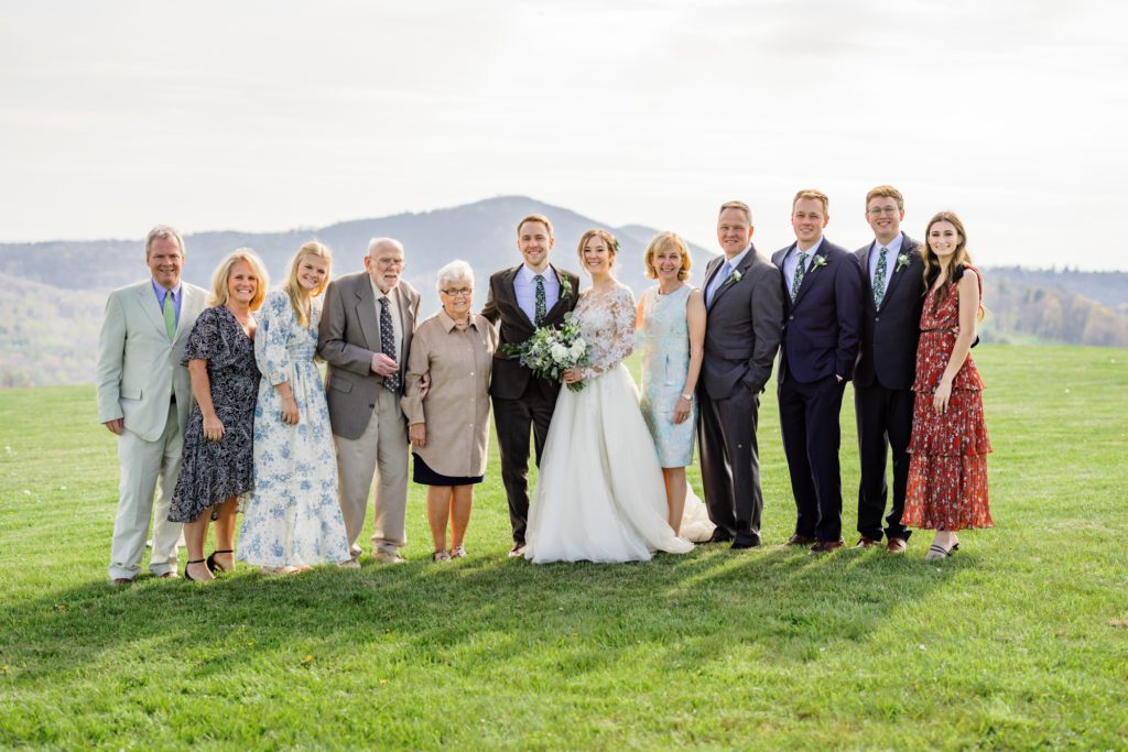 wedding couple standing with family and guests during outdoor wedding portraits