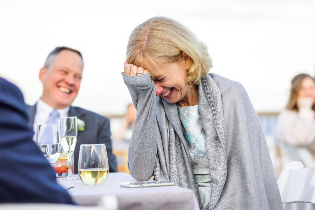 bride's mother putting her hand to her face laughing during speeches and toasts