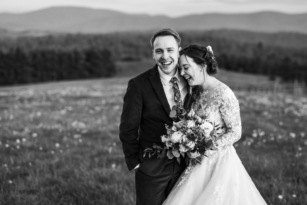 bride and groom embracing and laughing together during outdoor portraits wearing wedding attire