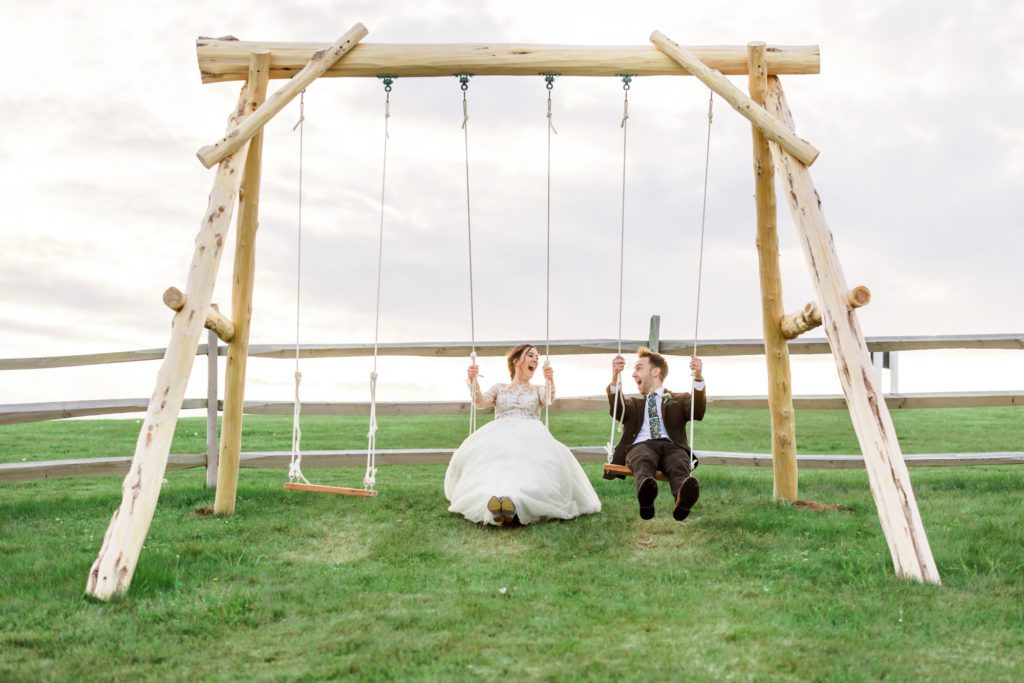 bride and groom swinging together during portraits
