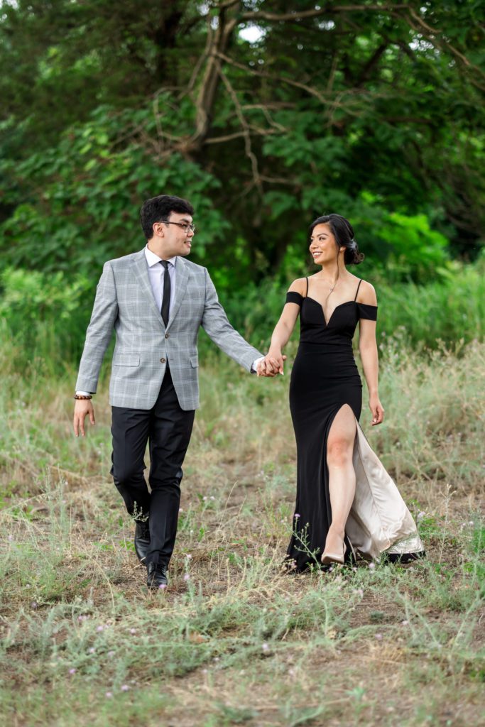newly engaged couple walking through field at elegant belle isle engagement session