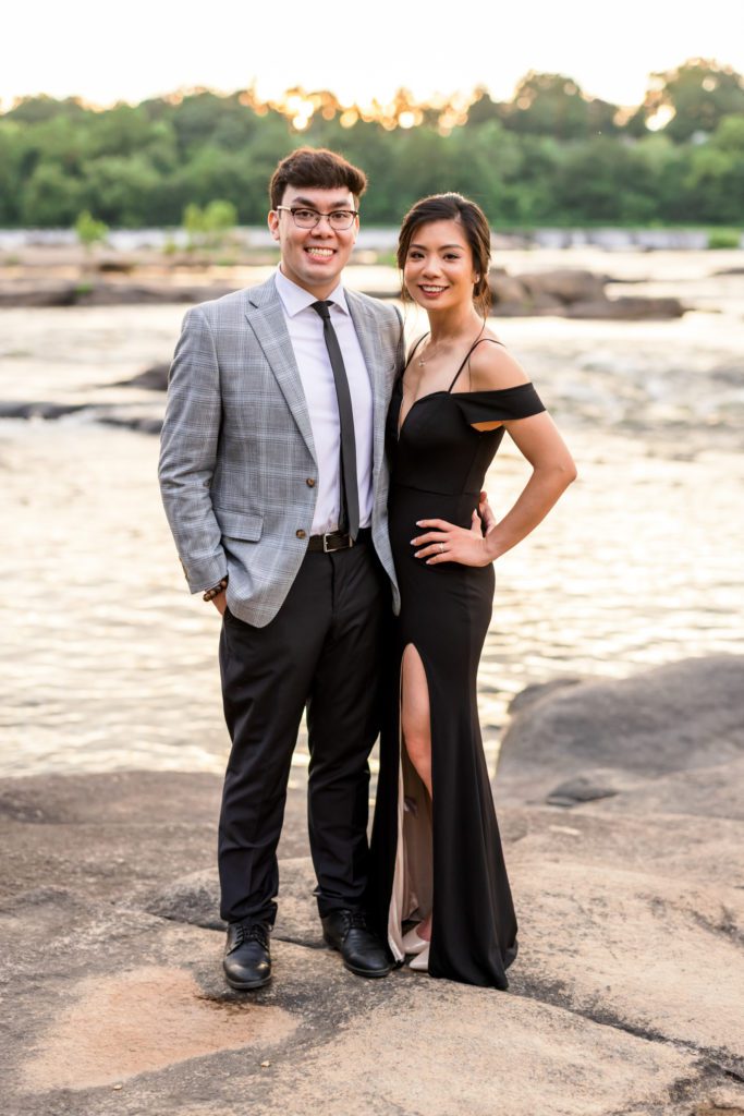 engaged couple standing on rock beside water at Belle Isle