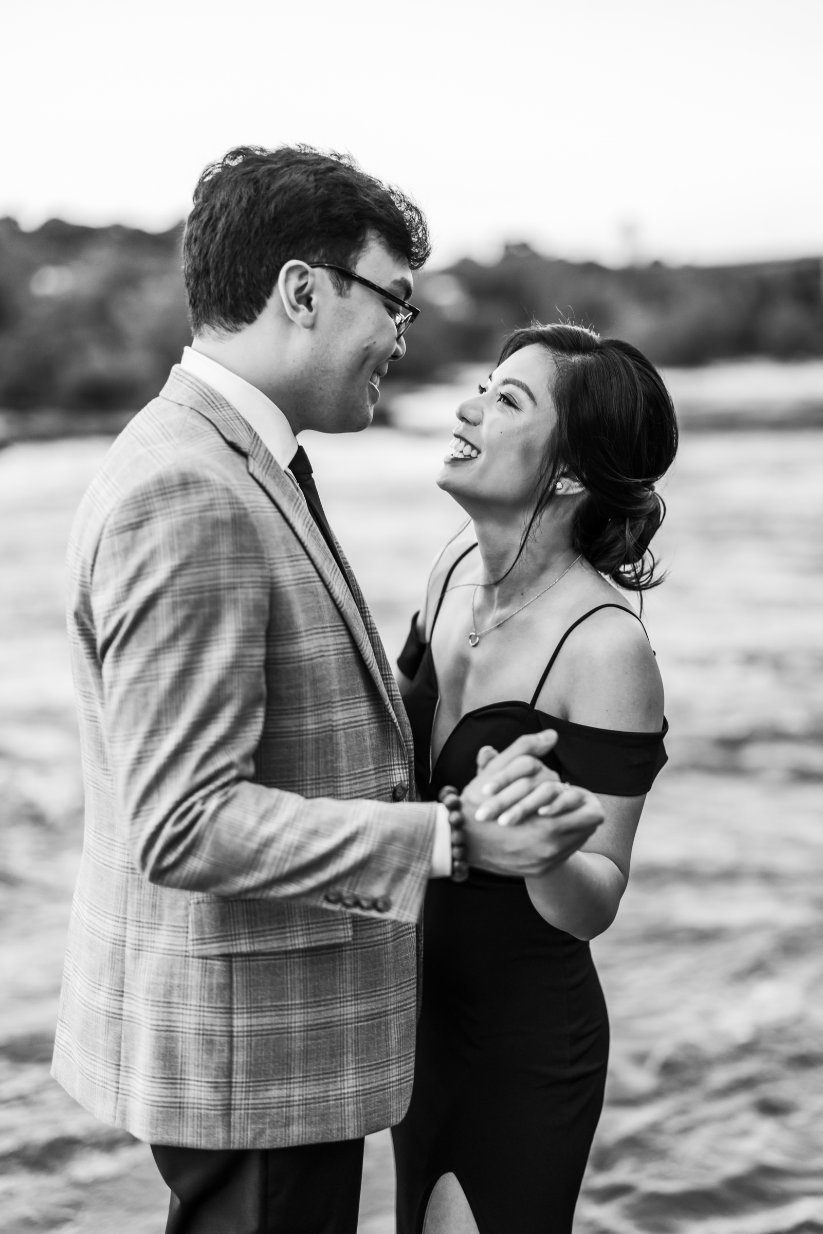 engaged couple dancing on rocks beside water at Belle Isle engagement session