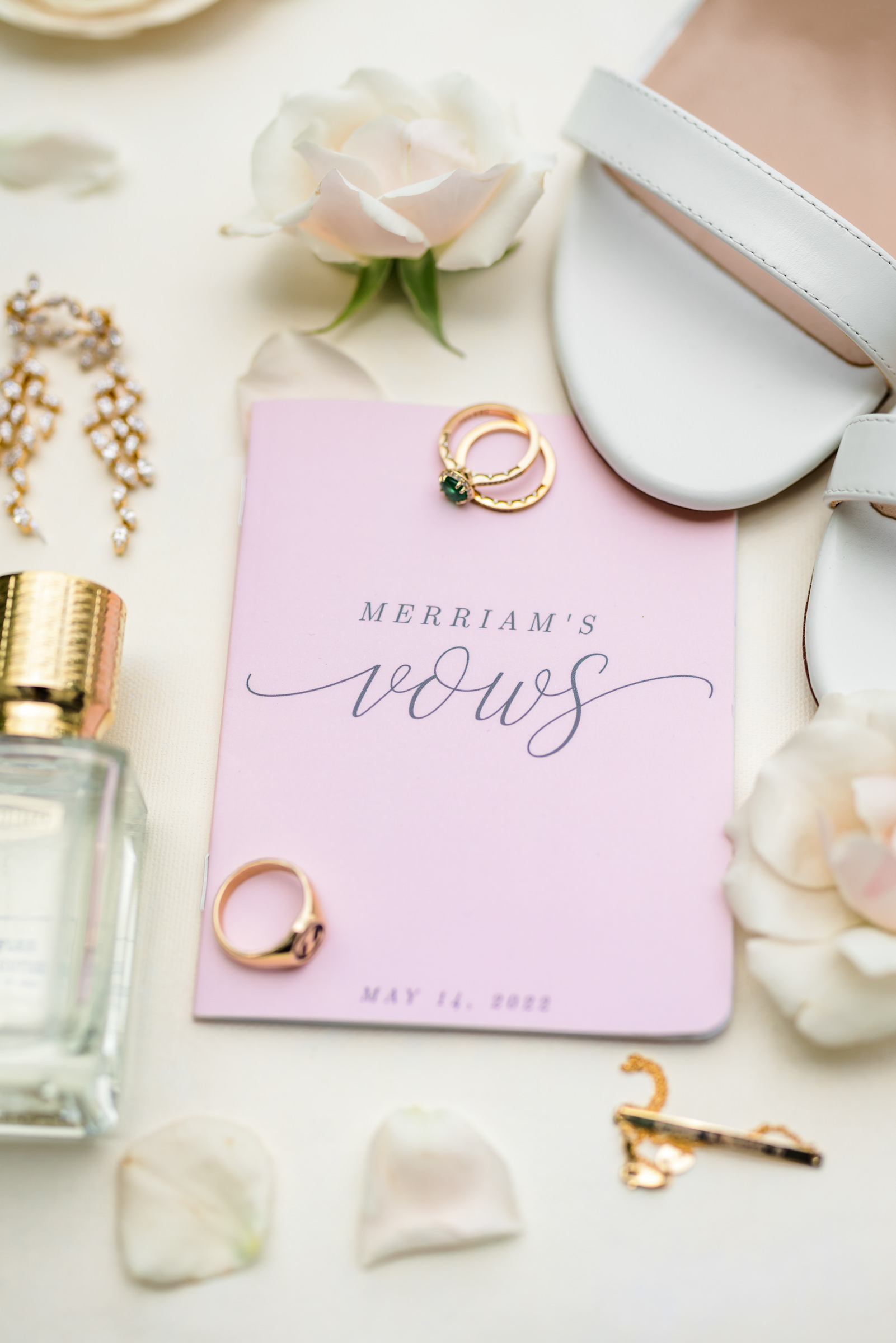 pink vow book and bridal details with shoes, perfumes, jewelry