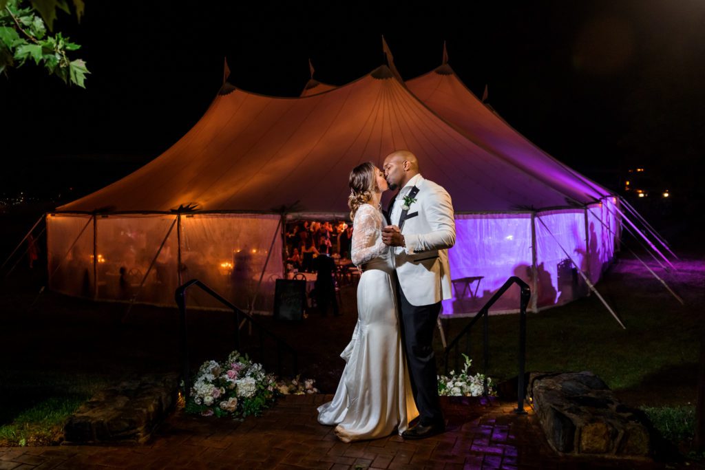 bride and groom dancing with reception tent in background 