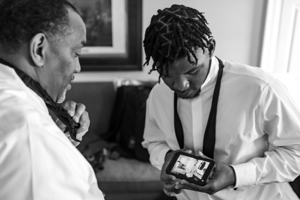groomsmen showing other groomsmen video on phone while getting ready 