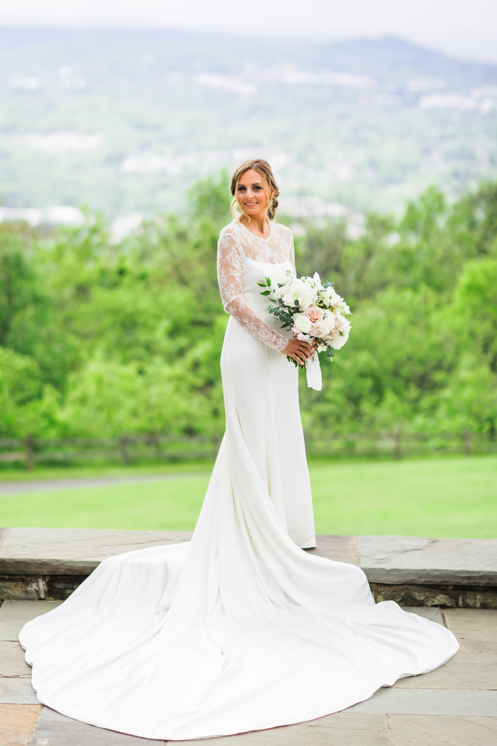 bride holding bouquet wearing wedding dress with long lace sleeves