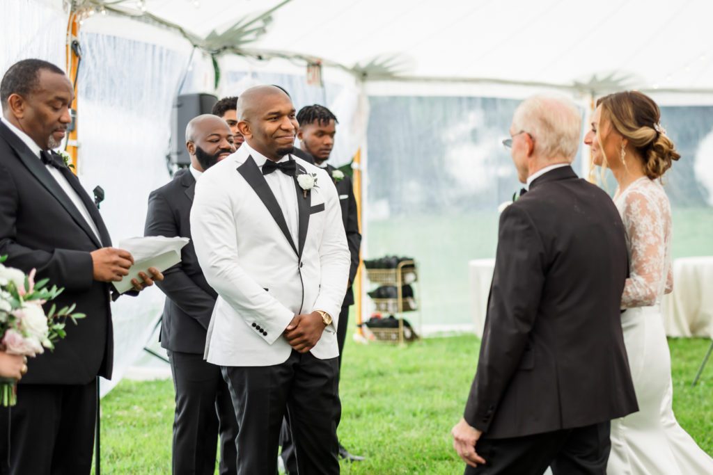 groom standing at alter while bride is walked down with father before ceremony