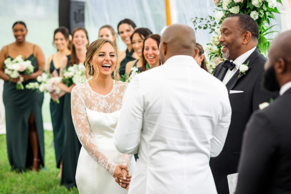 bride laughing while groom reads vows