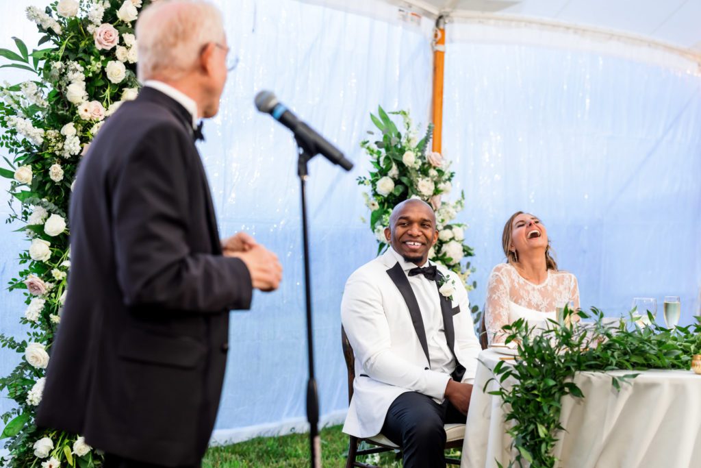 wedding couple laughing and listening to toasts at reception
