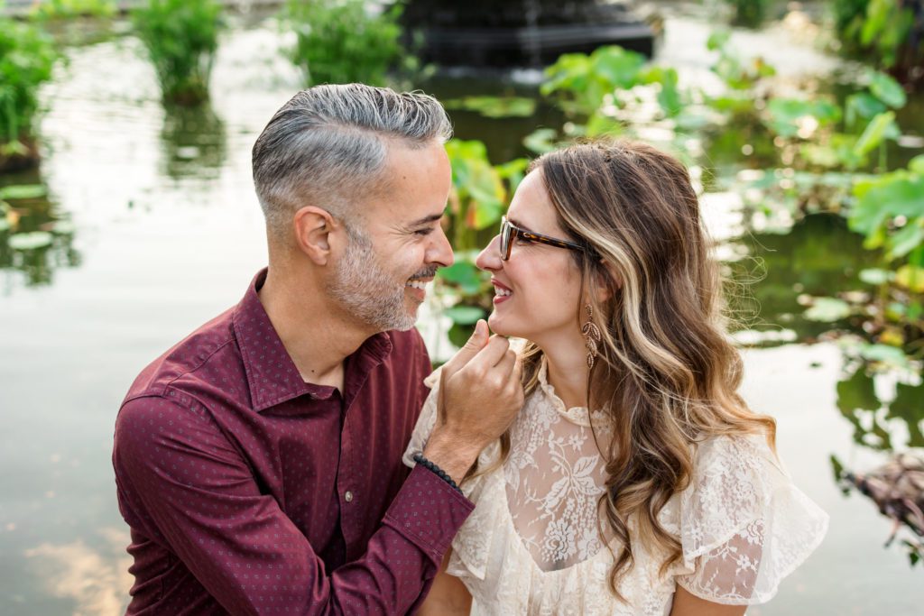 man holding woman's chin and smiling at her during couples session