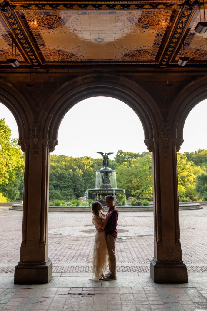 engaged couple standing in Bethesda Terrace embracing
