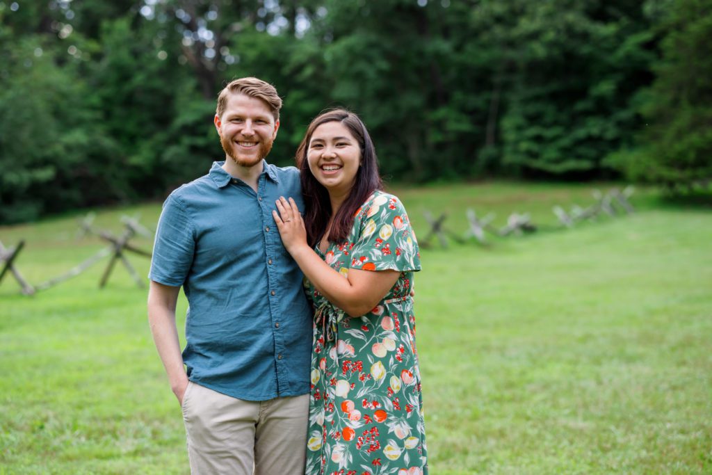 woman wearing green dress with florals and man wearing blue shirt at summer shenandoah national park engagement session