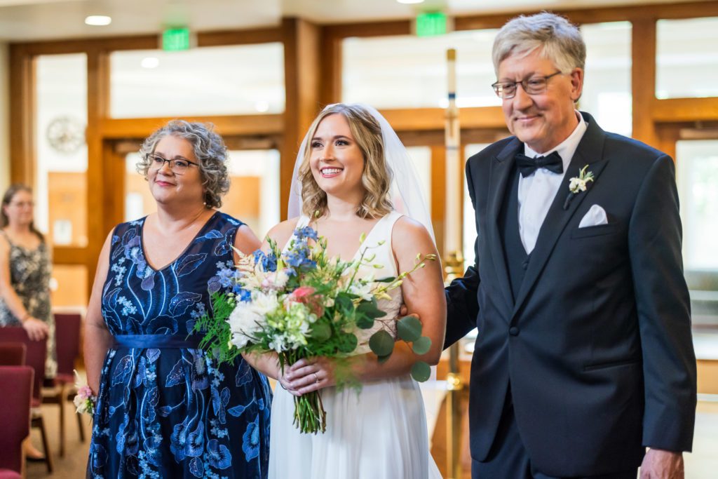 bride being walked down aisle by her parents 