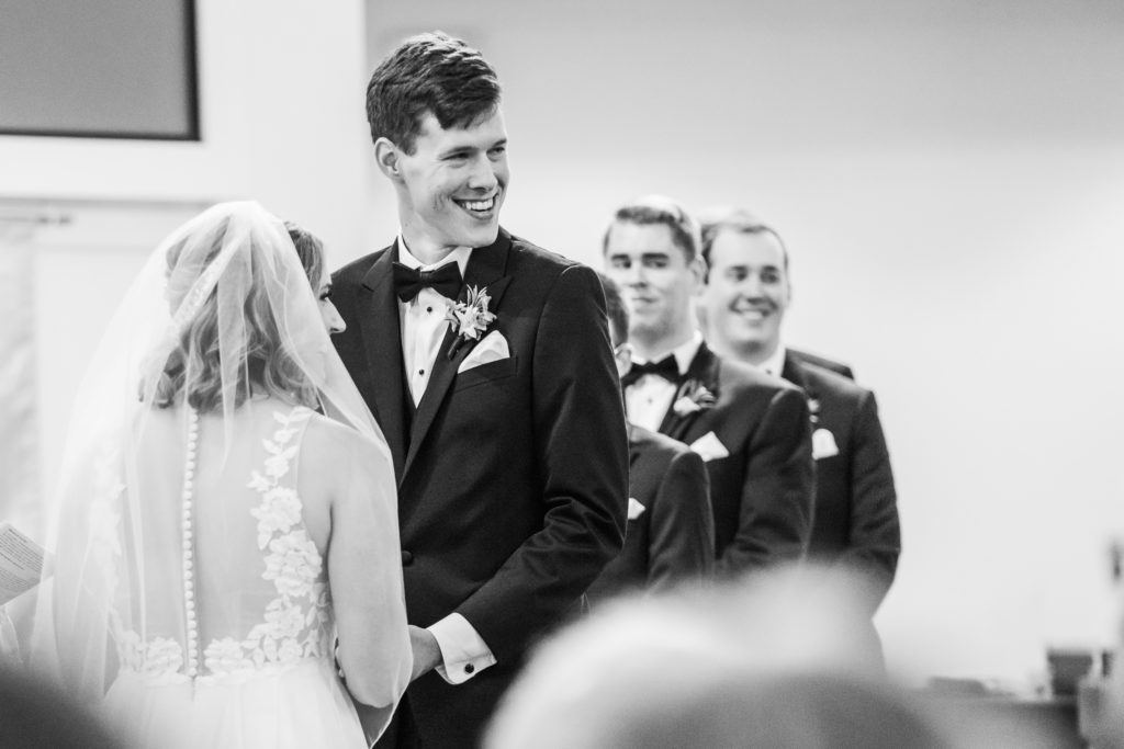 black and white portrait of bride and groom holding hands at wedding ceremony