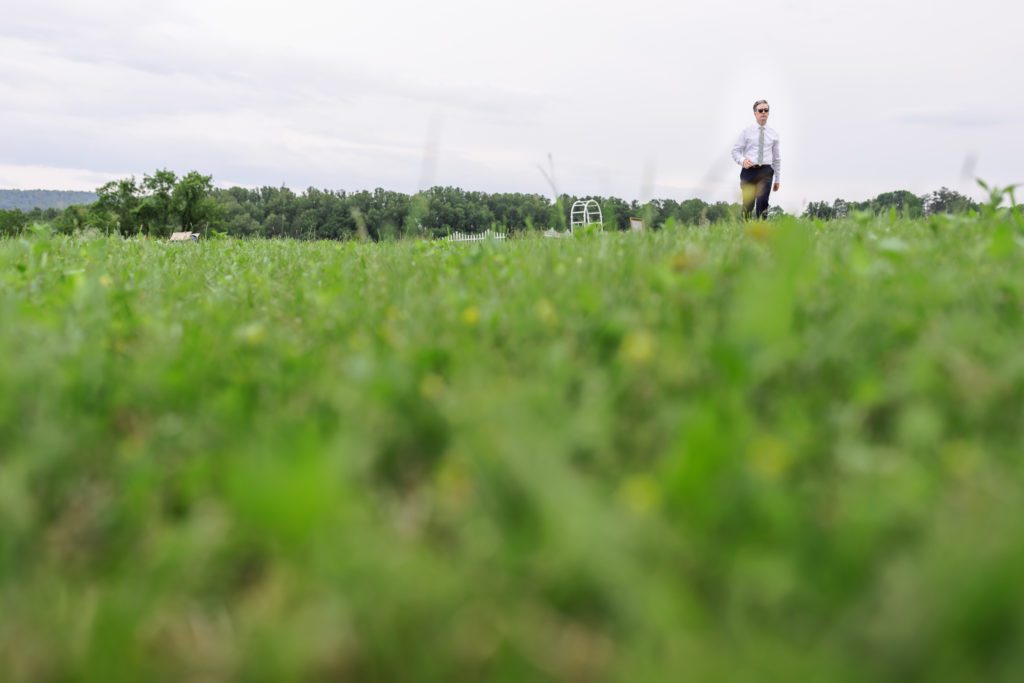 close up of grass with groom playing outdoor games before backyard wedding