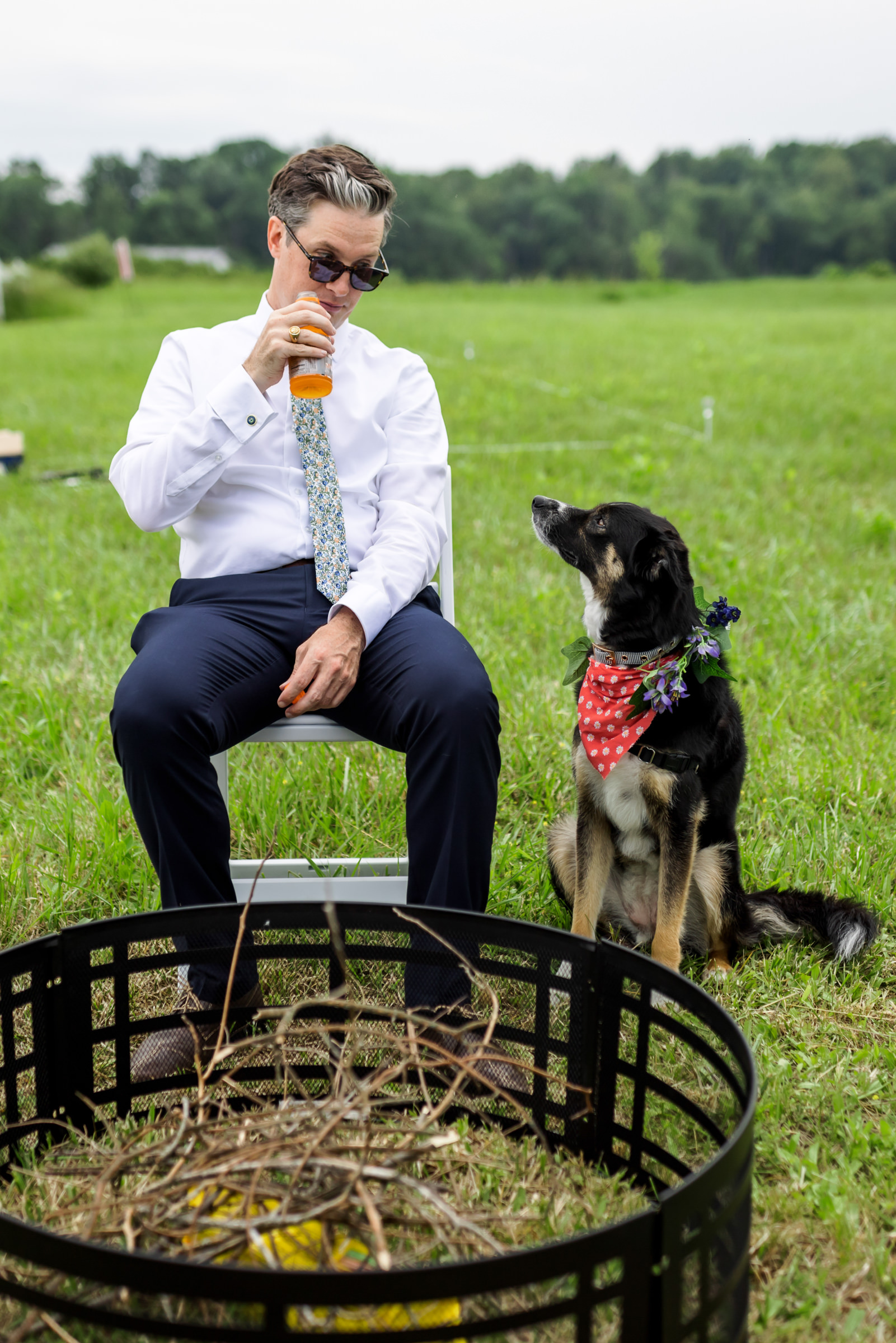 groom sitting with dog at outdoor wedding reception