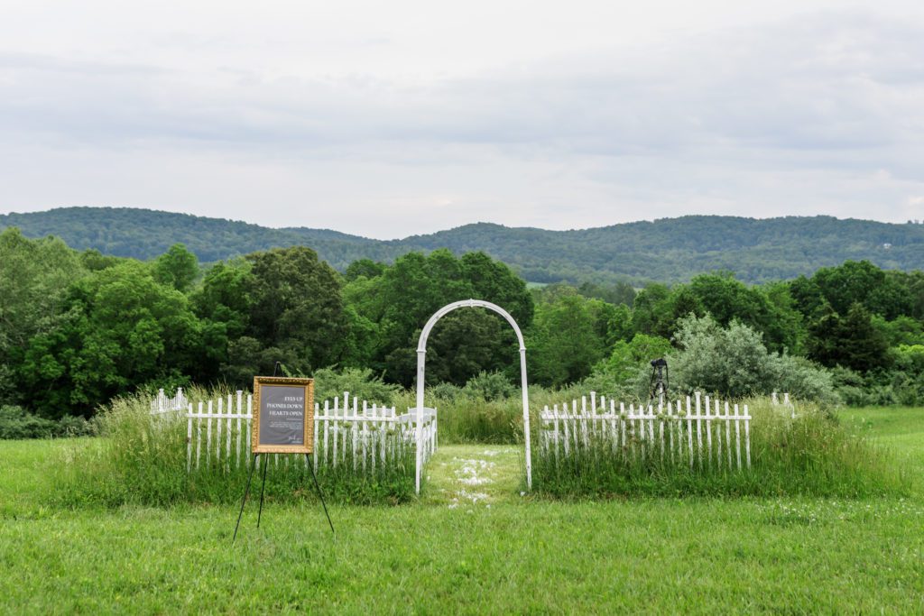 wide view of backyard wedding ceremony with rounded arch and chalkboard welcome sign