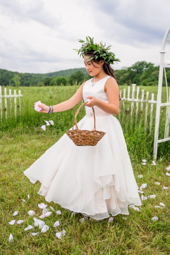 flower girl tossing flower petals on the ground before backyard lexington wedding ceremony