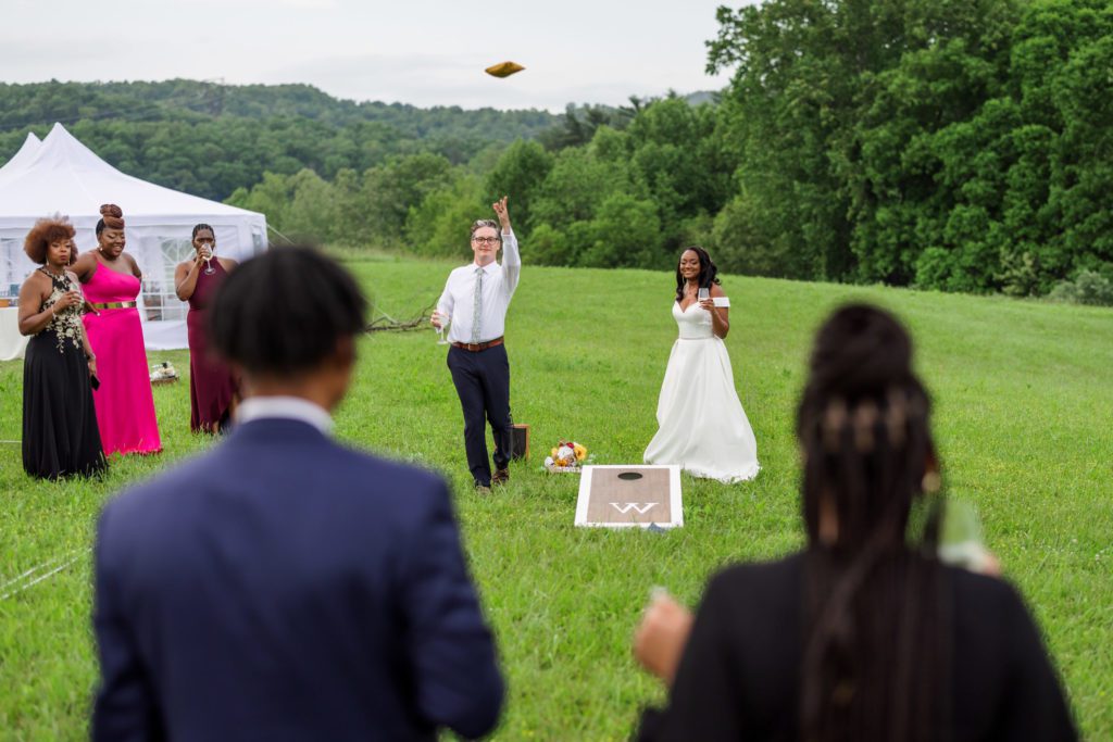 bride and groom playing corn hole 